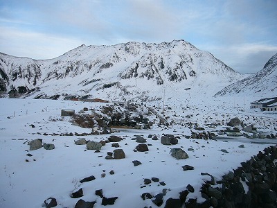 窓の外の景色。暗い水色の空に立山が突き出している。