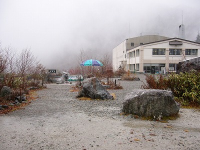 枯れ草枯れ木に囲まれたガス覆い雨降る砂利の広場