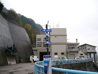 左手にコンクリートで覆われた山肌、右手にダム湖の細い欄干に挟まれた堰堤終点脇の小広場
