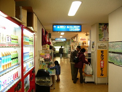 左脇に自動販売機、上には青色の案内板のあるレストハウス二階の通路