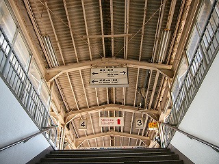 くすんだベージュの鉄筋の上に被せられたような波板の上屋を見上げて