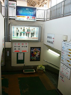 階段を下へくだりきる直前。プラスティックに夜のホテルの写真が焼き付けられた電照式広告灯を見上げる。地面は緑色だが所々はげていて、経年によりくすんだ黄色の点字ブロックが貼られてある。