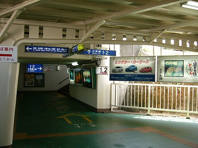 奥に薄暗い奥行きが見え、その中に「1・2小浜線方面」と白い字で書かれた背景色が青色の大きな電照式案内板が壁に取り付けられている。右は薄暗い奥行きへの入り口前であり、石の土手になっていてその前に策がしてある。