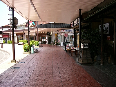 真新しく平らなアーケードですっかり影になった歩道。地面は曇った紅色の大きなタイルで作られてある。歩道は店を見せながらカーブしている。