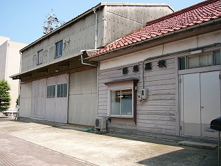 横板で覆われた木造の建物。屋根瓦は紅色。