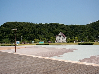 木造のデッキからパステルカラーのレンガの広場と古めかしい時計台を望む。