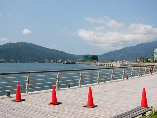 木製のデッキには赤いコーン、すぐ先は海だが、ずっと向こうの右手は埋め立て中で、雑然としている。