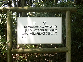 白いプレートに黒い字で書かれた説明板。太い木枠に吊られてある。