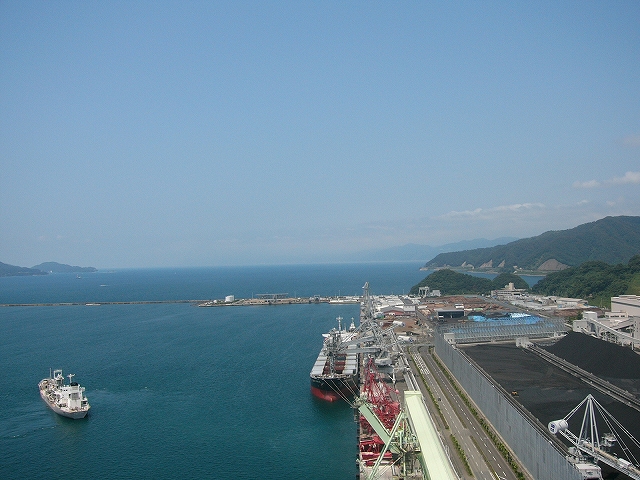 岸壁。右手には大きな敷地に黒い砂のようなものが溜め込まれている。