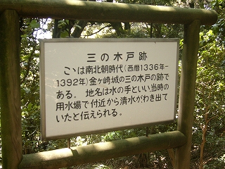 白いプレートに黒い字で書かれた説明板。太い木枠に吊られてある。