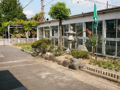 幅2mぐらいの細長い敷地に作られた庭。一本の小高い木、花壇、石灯籠、庭石などが配置されてある。