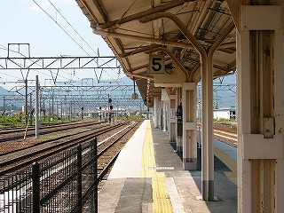 遠くに大きくカーブする構内に突き出す5番線。線路の幅が左に終わる所には草むら。5番線はのりばの縁が真新しい白いコンクリートでそれ以外は真新しいアスファルトになっている。