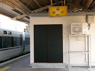 黄色地に黒字でExit出口と書かれ、赤の矢印が書かれた電照式案内板。