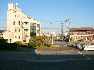 駅正面。短い横断歩道を渡るとロータリーの中央部に行き着く。さらに先には国道に出る2車線の道路が延びているが、全体的に交通量は多くない。