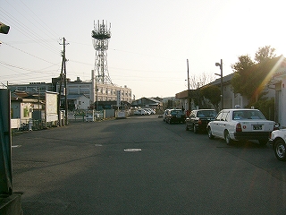 アスファルトの敷地を縦長に見て。ほとんどが影に覆われている。