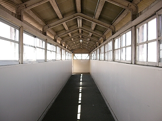 白い壁と木枠の窓のある跨線橋内。