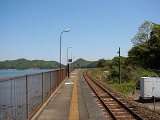 海、柵、ホーム、一線の鉄路。遠くに低い山並みが見える。