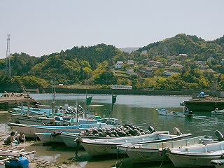 船と漁港、向こうの海岸に列車が停まっている。