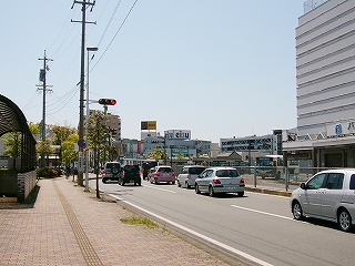 歩道、道路、走りゆく自動車、デパートの建物。