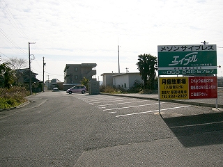 アスファルトの敷地。右手には横に何本も白線が引かれて駐車場が作られてある。