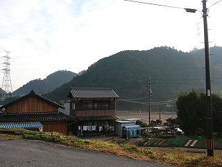 少しだけ高い位置から見た二件の田舎の家。その奥は畑で、その次にはすぐ山がある。