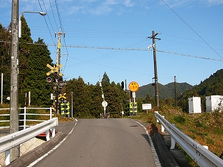 坂を上った所にある踏切と真っ青な空。奥は森。