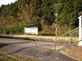 奥に林、その手前に上り線ホームの待合所、そしてこちら側から見てすぐ手前は跨線橋のの上り口が写っている。