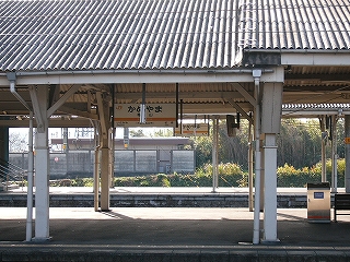 隣のホームと駅名標に、さらにその向こうのホームと駅名標が重なった風景。人は誰も居ない。