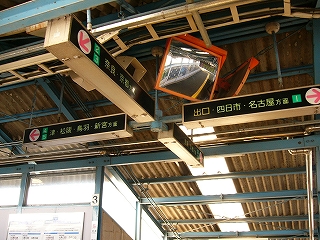 階段を上りきる少し手前から天井を見上げて。細長い電照式方向案内板が十字に出ていて、そのすぐ近くに大きなミラーが取り付けられている。