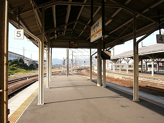 上屋の途切れる少し前から見た光景。上屋は少し先で終わってしまうが、ホームもずっと向こうまでカーブしながら続いている。上屋はもうすぐ終わるにもかかわらず、上屋の下には時計と駅名標が設置されている。
