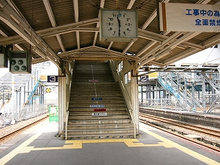 手前に上屋から吊られた四角い時計、その奥に階段。