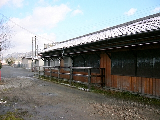 駅舎の側面を右斜めに見て。駅務室内に当たる窓ガラスに排他が打ち付けられている。