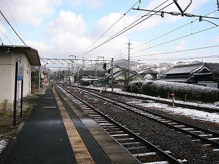 右手に線路内、その右には人家の垣根があり、民家の瓦屋根がいくつか見えている。