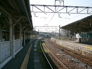 少し遠くで右にカーブする線路内。左右には床面に陰を作った上屋が写っている。