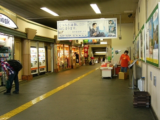 地面がアスファルトの縦長気味のコンコース。左側に二件のお店が入り、右手には弁当を売る露店が一件。