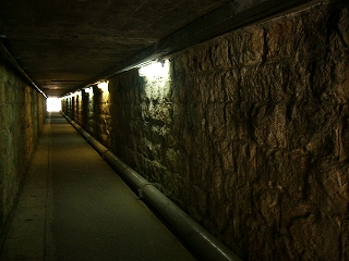 通路の中に入って。内部は照明が少なく、両脇は石積み。
