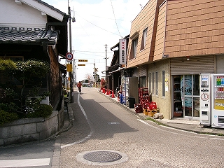 かなり小さな道角。右の角に酒屋。
