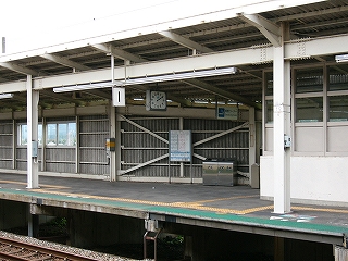 縦に波が入った灰色の板と、白い鉄筋で組まれた壁に沿うように造られた、階段への下り口付近。