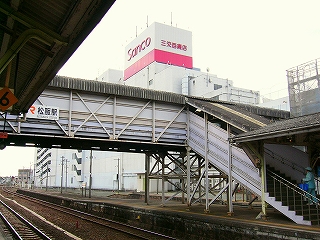 濃い桃色の三交百貨店の屋上看板と白い跨線橋。