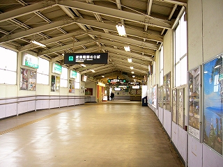 壁は白色、床はクリーム色で屋根も高い跨線橋内部。壁には大きな窓が多く明るい。