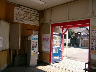 券売機、路線図のある駅舎内。出口から外を見通して。