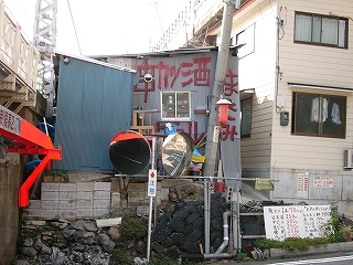 さまざまな石を寄せ集めて作られた石垣の上にある灰色のトタン壁の建物。