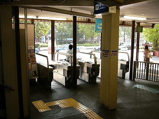 屋根の下に4レーンの自動改札。改札を出たらすぐに野外になり、ロータリーがうっすら見えている。