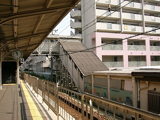 左から順に、乗り場に面して立てられた長い柵の連続、4番線の線路、こちら側に下りてきて南出口につながっている跨線橋の屋根と壁に囲われた階段。