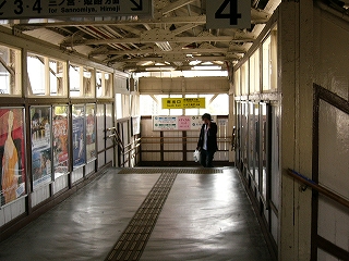 跨線橋の突き当たり手前10mの位置から撮影。両脇の壁の上部と突き当たりの壁の上部には窓から光が入ってきていて明るい。