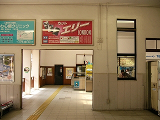 人を横に5人くらい並べた幅の間口が目の前にある。高さはそれほどなく、天井までの部分は壁があり、そこに二枚の大きな額入り広告が設置されてある。間口からは、次の大きな空間の奥に自動改札が横に並んでいるのが見えている。