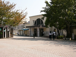 駅舎から少し離れて斜めに見る。両脇に葉を茂らせた木。