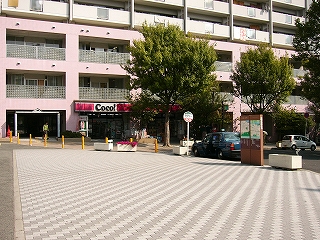 南出口改札を出て左を見た光景。レンガ敷きの敷地がロータリーの道路まであり、左奥にマンション一階のコンビニが写っている。