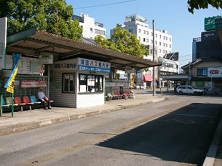 薄い波板が屋根になっている縦長のバス乗り場。屋根の下に一人掛けの椅子がいくつも並んでいる。バス乗り場中央あたりには古めかしい案内所がある。