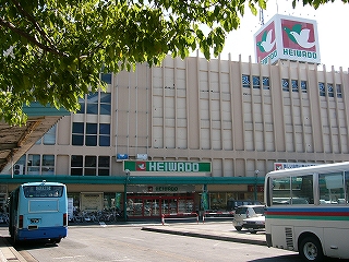 緑の葉陰から五階建ての大きな建物の平和堂を見て。